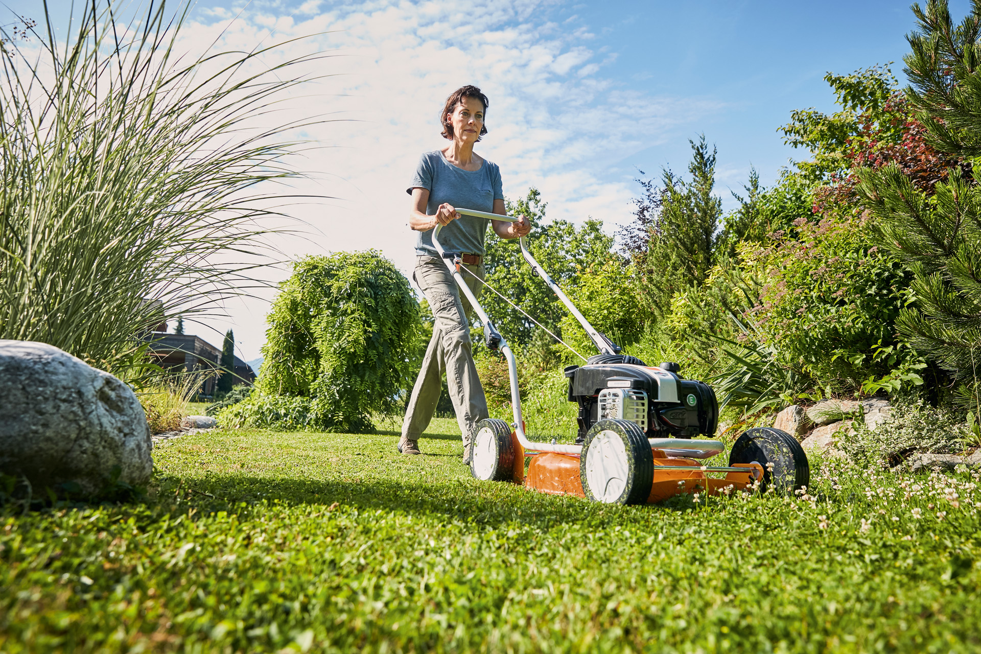 Kobieta używająca spalinowej kosiarki do mulczowania STIHL RM 2 R na terenie zielonym