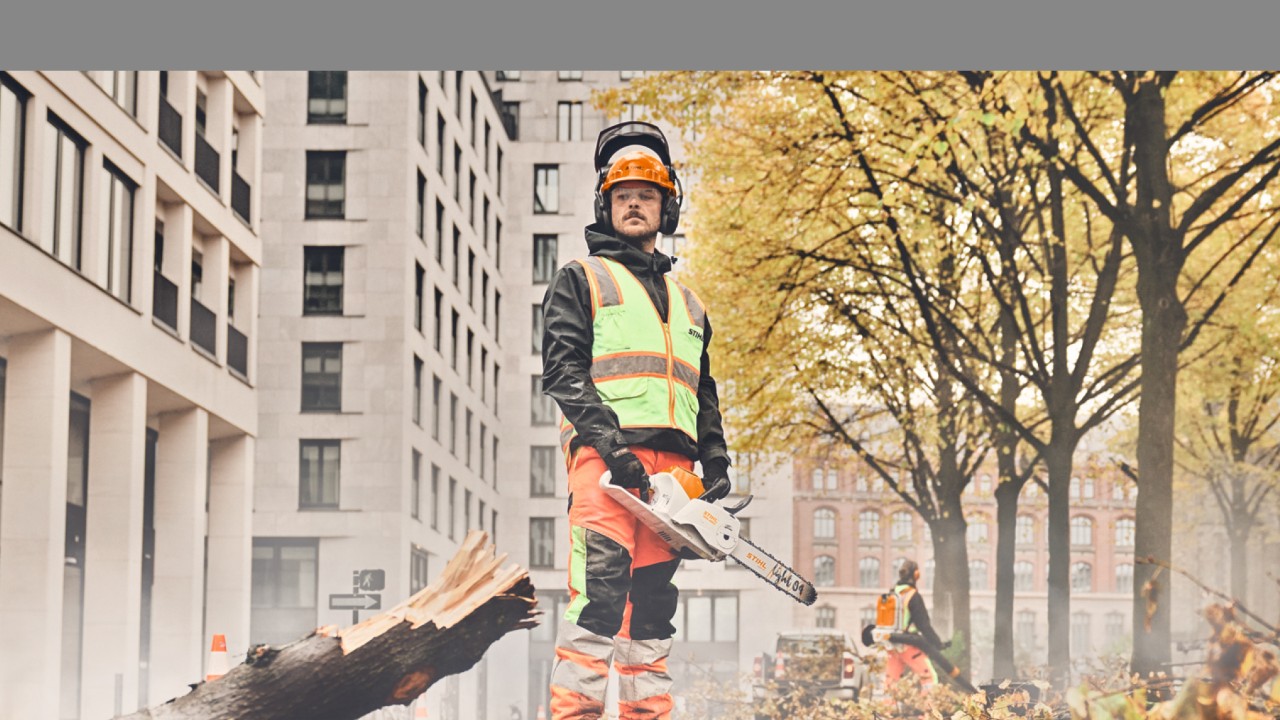 Mężczyzna stojący z pilarką łańcuchową STIHL przed drzewem