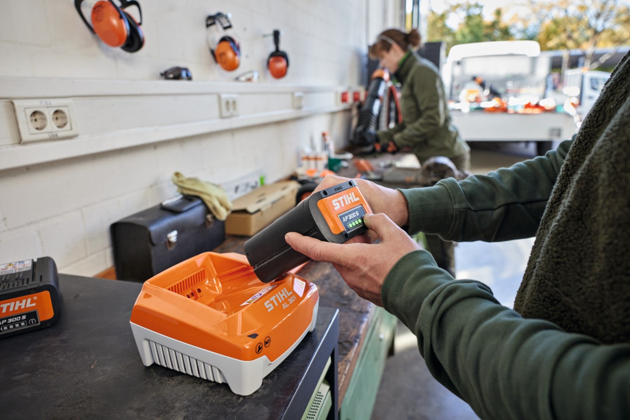 Osoba wkładająca akumulator STIHL AP 300 S do szybkiej ładowarki STIHL AL 301