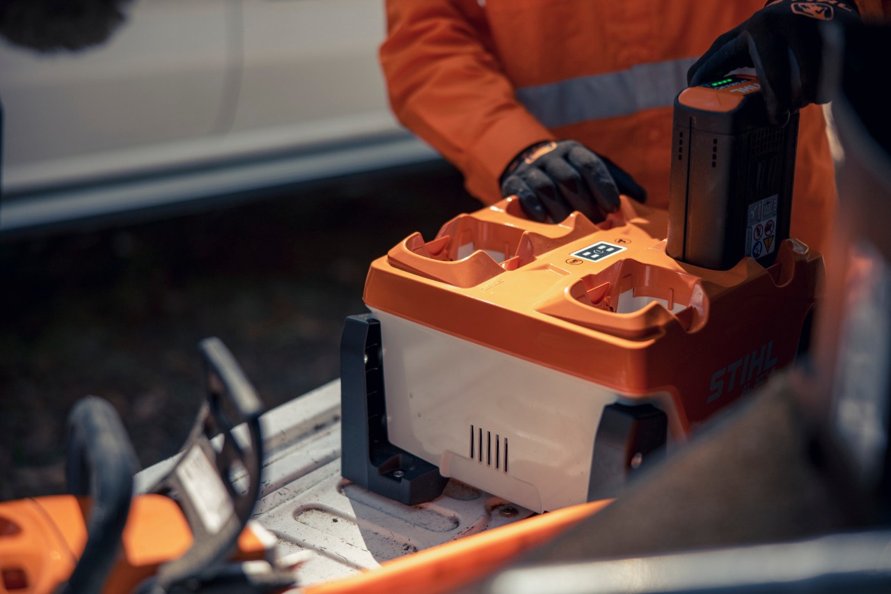 Mężczyzna w magazynie z urządzeniami i akumulatorami STIHL noszący modułowy system pasów STIHL ADVANCE X-Flex 