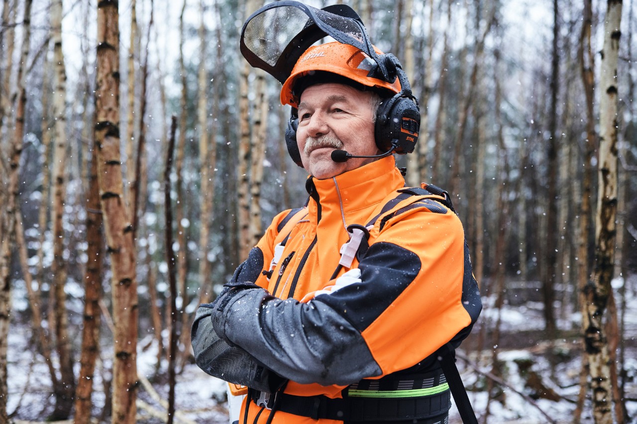 Mistrz leśnictwa Martin Nolte stoi w lesie w odzieży STIHL ze skrzyżowanymi ramionami
